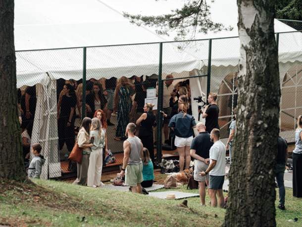 Návštěvníci před stanem expa mezi stromy v areálu Vista Resortu
